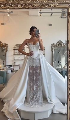 a woman taking a selfie in front of a mirror wearing a white wedding dress