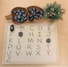 two wooden spoons with letters and numbers sitting on top of a table next to a potted plant