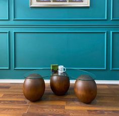 three wooden balls sitting on top of a hard wood floor next to a blue wall