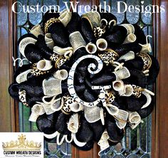 a black and white wreath with leopard print bows on the front door for halloween decor