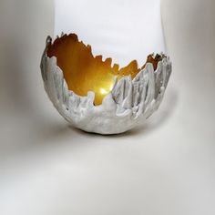 a white bowl that has some gold in the center and mountains on it's side