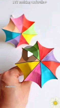 three colorful umbrellas being held up in the air by someone's hand with their thumb