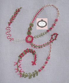 a cross stitch pattern with pink and green beading on it's side, next to a white piece of cloth