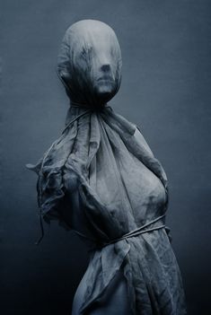 a mannequin wearing a white scarf and headdress in front of a gray background