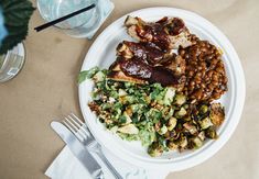 a white plate topped with meat and beans