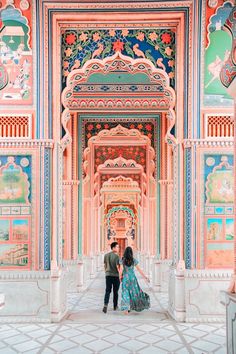 an engaged couple standing in the middle of a colorful building with intricately painted walls