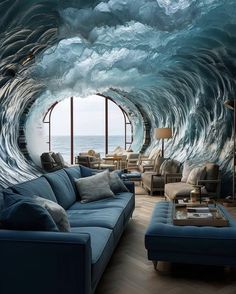 a living room filled with blue couches next to an ocean wave wallpaper mural