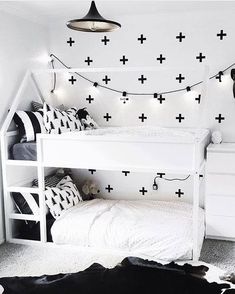 a white bunk bed with black crosses decals on the wall and lights above it