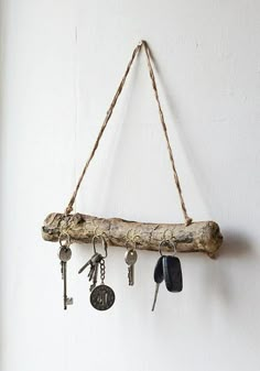 several keys hanging from a wooden branch on a wall