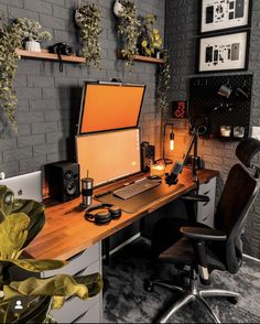 a desk with a computer on top of it next to a plant and potted plants