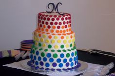 a multi - colored polka dot cake with the letter m on top