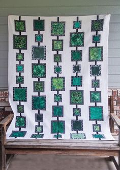 a green and white quilt sitting on top of a wooden bench