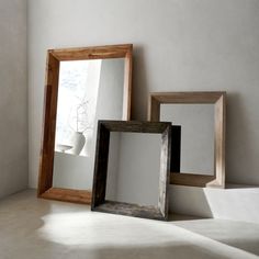 three wooden frames sitting next to each other in front of a mirror on the floor