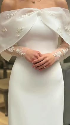 a woman wearing a white wedding dress with an off - the - shoulder top and long sleeves