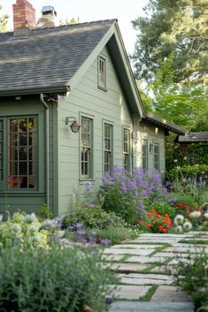 a small house with lots of flowers in the front yard and walkway leading up to it