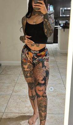 a woman with tattoos taking a selfie in the mirror while wearing her leggings