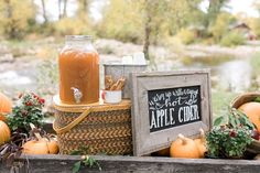 an apple cider sits on a picnic table with apples and other fall decorations around it