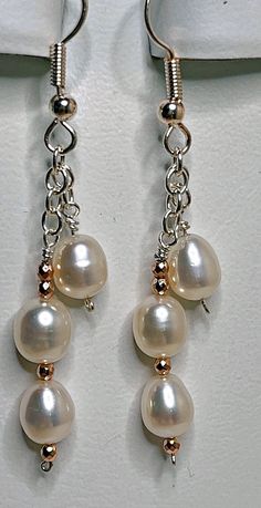 Take three pure white freshwater pearls per earring, attach them to sterling silver chain, and dangle them from French wires. That's the recipe for beautiful earrings that will go with everything. Just for fun, add in a few tiny rose gold beads; that's the finishing touch. These earrings have a 1 1/2 inch drop, and are 2 3/8 inches long overall. White Pearl Chain Earrings In Sterling Silver, Sterling Silver White Pearl Earrings With Pearl Chain, White Sterling Silver Pearl Chain Earrings, Sterling Silver White Pearl Chain Earrings, White Nickel-free Dangle Pearl Earrings, Unique Diy Earrings Ideas, Easy Diy Earrings, Diy Earrings Pearl, Handmade Earings