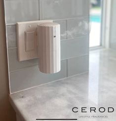 a wall mounted device on the side of a white tiled wall in a kitchen with glass doors