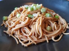 a black plate topped with noodles and peas