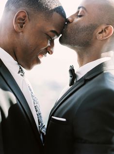 two men in suits are kissing each other