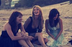 three women sitting on the beach laughing