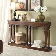 a wooden table with two vases on top of it and pictures above the table