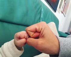 a close up of a person's hand holding something in their left hand on a couch