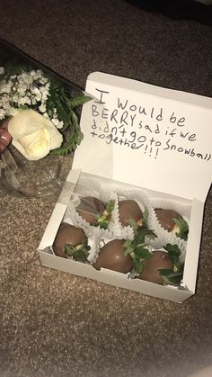 chocolate covered strawberries are in a box on the counter next to flowers and a note