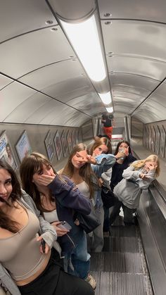 a group of young women riding an escalator down a subway train next to each other