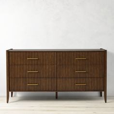 a wooden dresser with four drawers and two brass pulls on the top, against a white wall