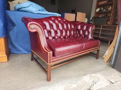 a red leather couch sitting on top of a floor next to a pile of boxes