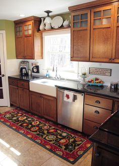 a kitchen with wooden cabinets and an area rug on the floor in front of the sink