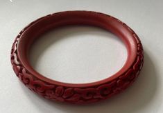 This vintage Chinese carved red cinnabar bangle is a stunning piece of jewelry that is sure to make a statement. The bangle features intricate carvings of traditional Chinese motifs, such as dragons, flowers, and geometric patterns, all done in a vibrant red hue. Cinnabar is a mineral that has been used in Chinese art and jewelry for centuries, prized for its rich color and durability. This bangle would make a beautiful addition to any jewelry collection and is sure to be a conversation starter. Carved Bangle Bracelet For Gift, Red Carved Jewelry For Wedding, Carved Bangle Bracelet As A Gift, Traditional Carved Round Bangle, Traditional Carved Bangle, Traditional Round Carved Bangle, Intaglio Bangle Bracelets As A Gift, Intaglio Bangle Bracelet As Gift, Red Vintage Bangle For Wedding