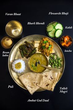 a plate filled with different types of food on top of a black tablecloth next to bowls and spoons