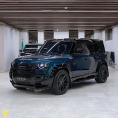 two suvs parked in a parking garage, one is blue and the other is black