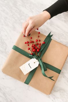 a present wrapped in brown paper with a green ribbon and red berries on the top