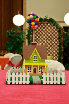 a small toy house sitting on top of a table next to a white picket fence