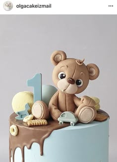 a teddy bear sitting on top of a blue cake covered in icing and chocolate