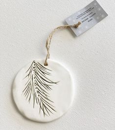 a ceramic ornament hanging on a string with a tag attached to the front