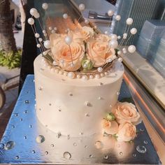 a white cake with flowers and pearls on it