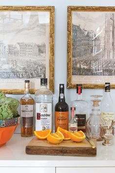 an assortment of alcohol bottles and oranges on a counter with pictures behind them,