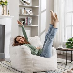 a woman laying on top of a white bean bag chair