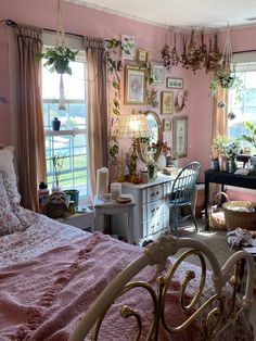 a bedroom with pink walls and lots of pictures on the wall above the bed, in front of a window