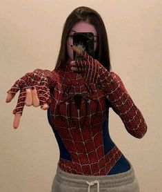 a woman taking a selfie with her cell phone in the shape of a spider - man