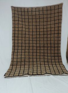 a brown and black checkered blanket sitting on top of a white bed coverlet