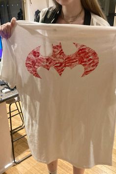 a woman is holding up a t - shirt with the symbol of batman on it