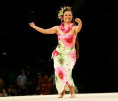 a woman in a flowered dress is dancing on the stage with her arms out