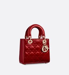 The Lady Dior bag epitomizes the House's vision of elegance and beauty. Sleek and refined, the timeless style is crafted in cherry red patent calfskin with Cannage stitching, creating the instantly recognizable quilted texture. Pale gold-finish metal signature D.I.O.R. charms embellish and illuminate its silhouette. Featuring a thin, removable leather shoulder strap, the small Lady Dior bag can be carried by hand or worn crossbody.. Dior Purse, Lady Dior Handbag, Dior And I, Womens Designer Bags, Dior Book Tote, Small Lady, Christian Dior Couture, Luxury Purses, Dior Handbags