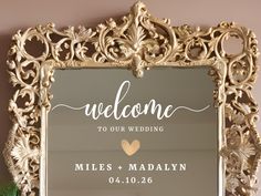 a welcome sign is displayed in front of a gold frame with a heart on it